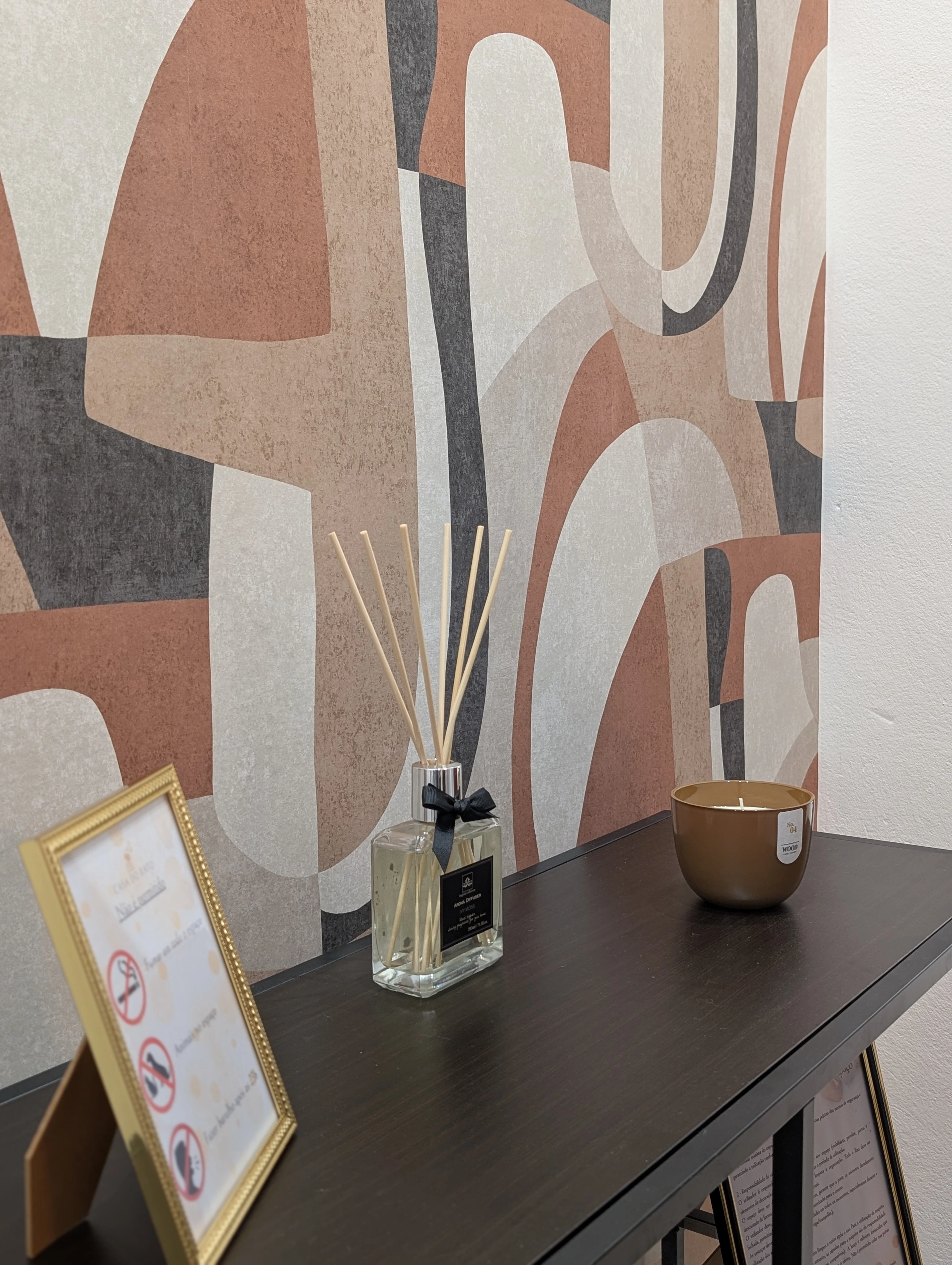 Decorative sideboard with a diffuser, framed sign, and graphic wall mural.