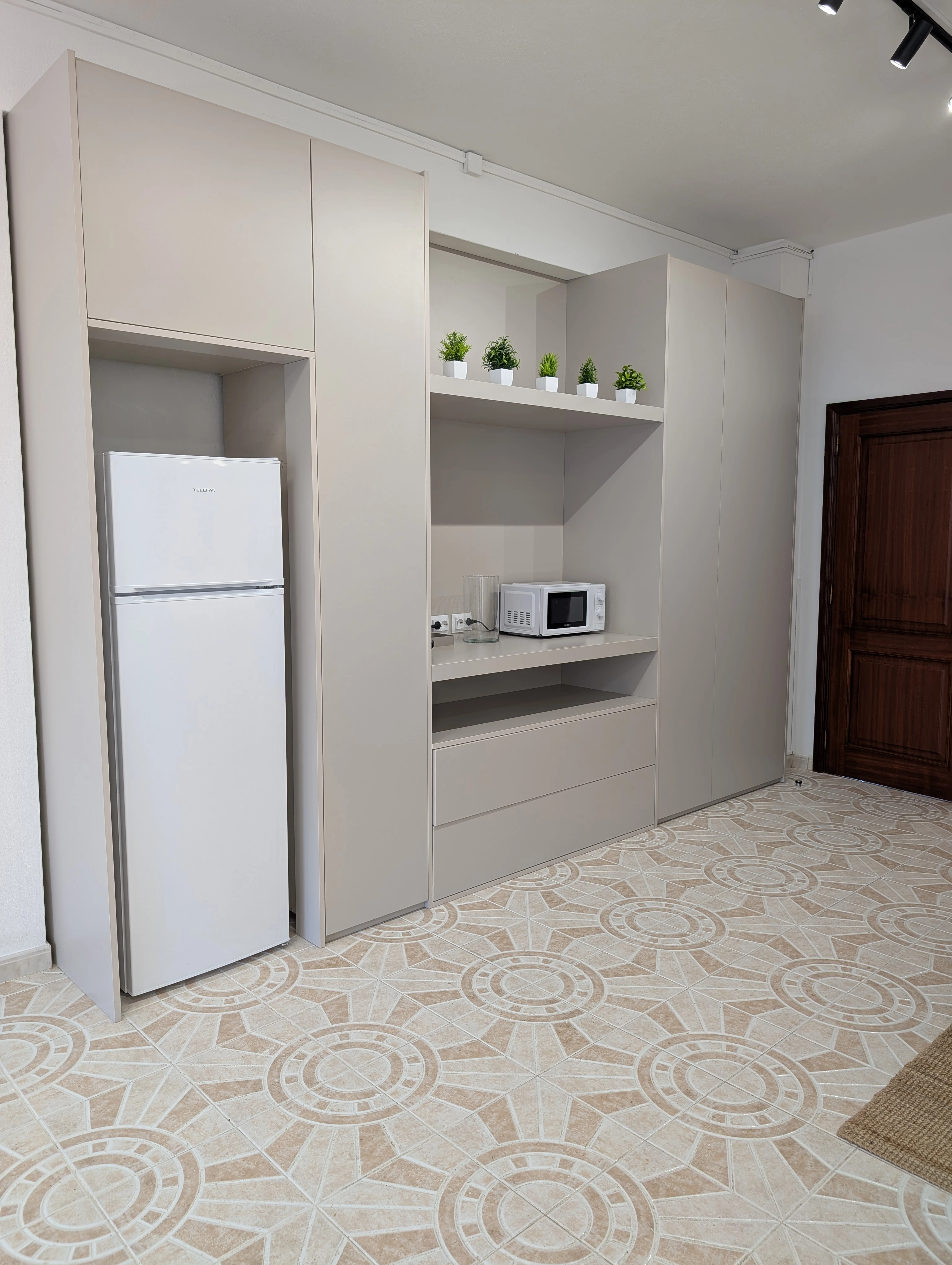 Support area with a refrigerator, microwave, coffee machine, and built-in storage.