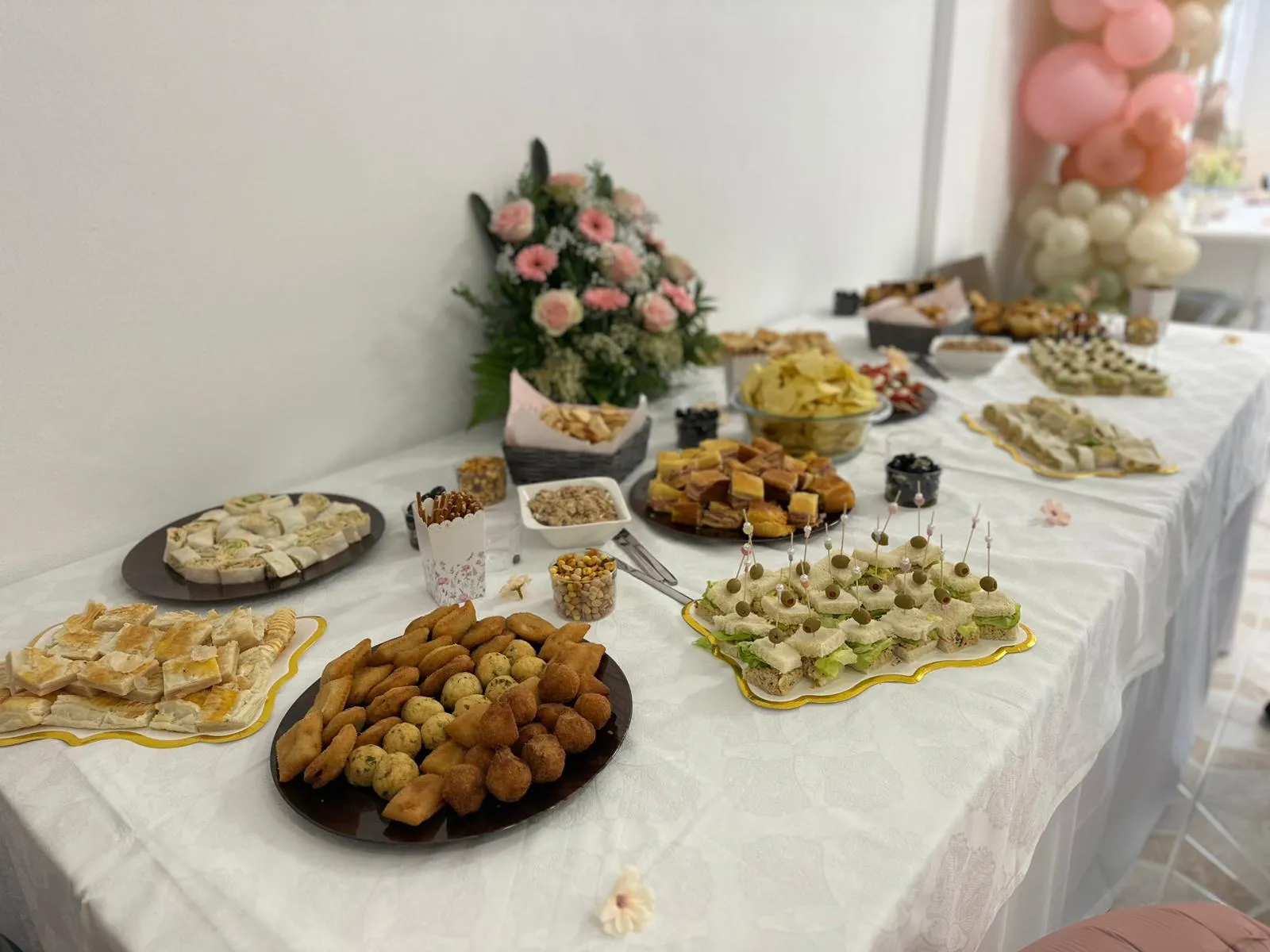 Buffet table with savory food, sweets, and a floral arrangement for a private event.