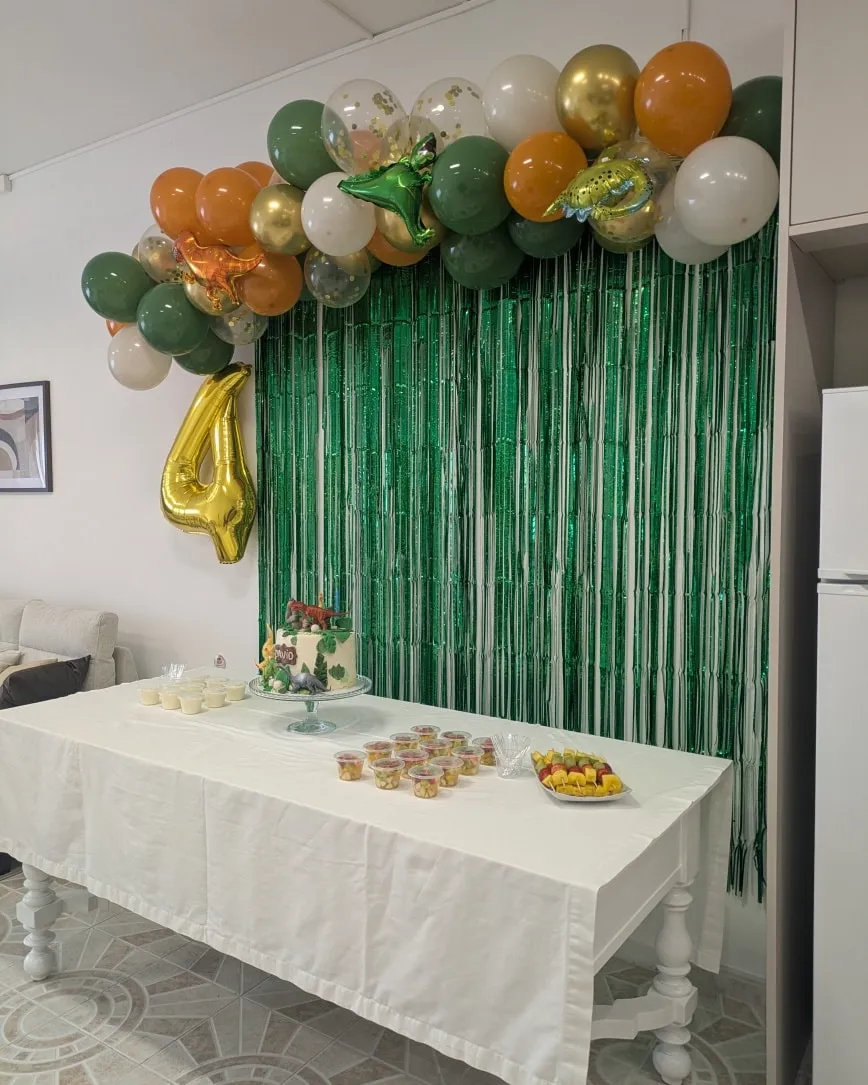 Themed birthday table with balloons, decorative curtain, and cake.